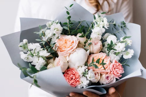 White and peach gift flower bouquet wrapped in grey paper